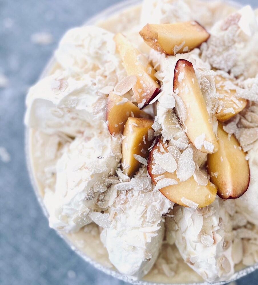 Meringue topped with sliced peaches and flaked almonds