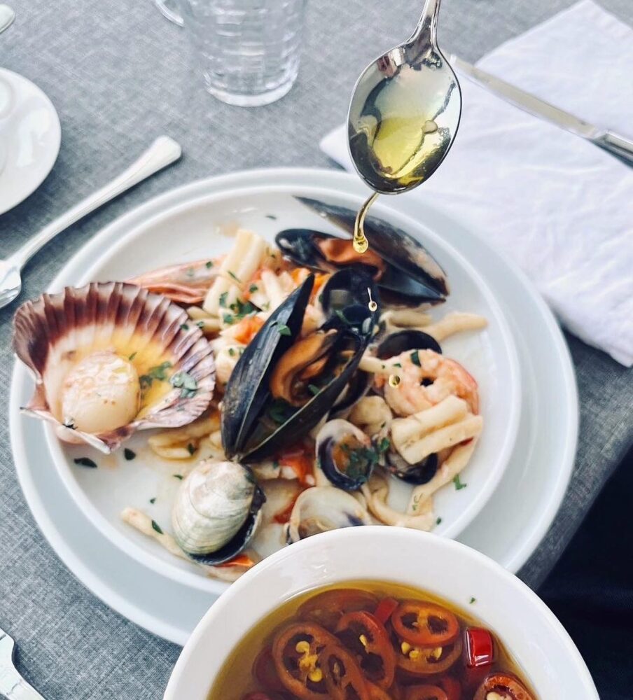 A plate of seafood finished with a spoon of olive oil