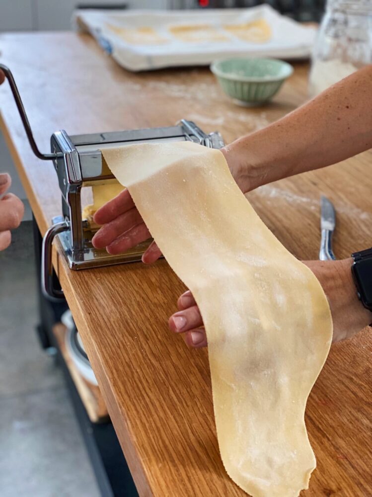 Rolling a sheet of fresh pasta through the machine